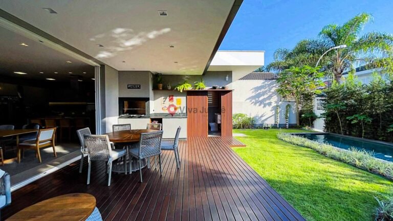 Área gourmet externa com churrasqueira, mesa de jantar e acesso direto ao jardim e piscina em casa moderna em Jurerê Internacional